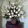 White floral arrangement in a ribbed vase with tall green spikes