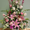 Pink lilies and roses arranged in a white vase