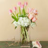 Pink tulips and blush roses in a clear glass vase with white hydrangeas