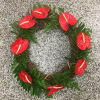 Red floral wreath with green foliage on a speckled gray surface