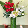 Red roses and white orchids arranged in a tall glass vase
