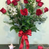Tall bouquet of red roses in a glass vase with a red ribbon