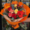 Bright mixed bouquet with gerbera daisies and carnations wrapped in orange paper
