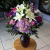 Bouquet of white lilies, pink roses, purple flowers in a dark vase