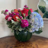 Bouquet of roses, hydrangea, and pink blooms in a dark green vase