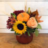 Pumpkin centerpiece with sunflowers, peach roses, and burgundy mums in a vase