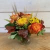 Orange and yellow floral arrangement in a speckled metal vase