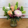 Mixed bouquet of roses, lilies, and a pink chrysanthemum in a glass vase
