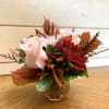 Pink roses and red mums arranged in a small glass vase