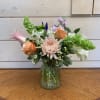 An arrangement of apricot roses and pink lilies with green bells of