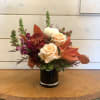 Peach roses and burgundy flowers arranged in a black vase