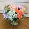 A petite arrangement of apricot roses, coral spray roses, apricot hypericum berries