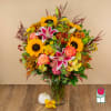 Mixed bouquet in a glass vase with sunflowers, lilies, and roses