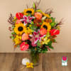 Mixed bouquet in a glass vase with sunflowers, roses, lilies, and anthuriums
