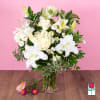 White lilies and roses arranged in a clear glass vase