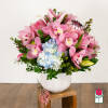 Pink orchid and lily arrangement with blue hydrangea in a white vase