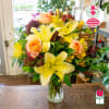 Bouquet of yellow lilies and peach roses in a glass vase