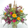 A lush vase design of richly colored autumn blooms, accented with cattails