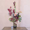 Tall orchid arrangement in a black vase with pink and white blooms