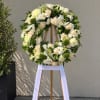 White and cream floral wreath on a wooden easel with a white ribbon