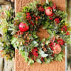 Autumn wreath with red berries and pomegranates on a textured wall