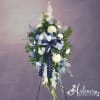 Tall standing spray of white and blue flowers with star-patterned ribbon on an easel stand