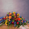 Colorful casket spray with roses, sunflowers, gerbera daisies, and blue flowers