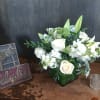 White roses and lilies arranged in a green vase.
