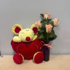 Plush mouse beside pale pink roses in a purple vase