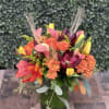 Colorful autumn bouquet in a green vase with orange, pink, yellow, and burgundy flowers