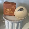 Bath bomb and boxed bath product on a small ceramic pedestal