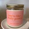 Pink-labeled jar candle with gold lid on a white ceramic pedestal stand