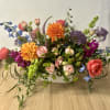 Mixed bouquet in a white rectangular vase with orange, pink, purple, and blue flowers