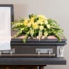 Yellow floral spray on top of a casket