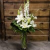 White lilies and snapdragons in a tall glass vase