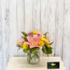 Pink lily and yellow daisy bouquet in a glass jar vase