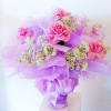 Pink roses with white baby's breath in a lavender-wrapped bouquet