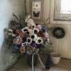 Mixed bouquet in a glass vase with roses, anemones, and dark accents