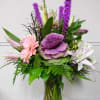 Mixed bouquet with purple, pink, and white flowers in a glass vase