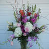 Tall mixed floral arrangement in a glass vase with pink and purple blooms
