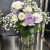 Lavender roses and white flowers in a clear glass vase