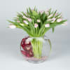 Pink tulips in a round glass vase with red orchids inside