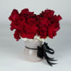 Red rose arrangement in a white vase with a black ribbon