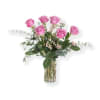 Pink roses arranged in a clear glass vase with airy greenery