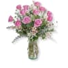 Pink roses arranged in a clear glass vase with airy filler flowers