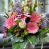 Pink gerbera daisies, lilies, and roses in a glass vase