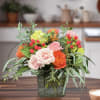 Mixed bouquet of pink and orange roses in a square glass vase