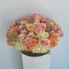 Round bouquet of pink and peach roses with pale hydrangeas in a glass bowl