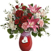 Red roses and pink lilies in a red vase with a heart charm