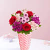 Red roses and pink flowers in a striped glass vase